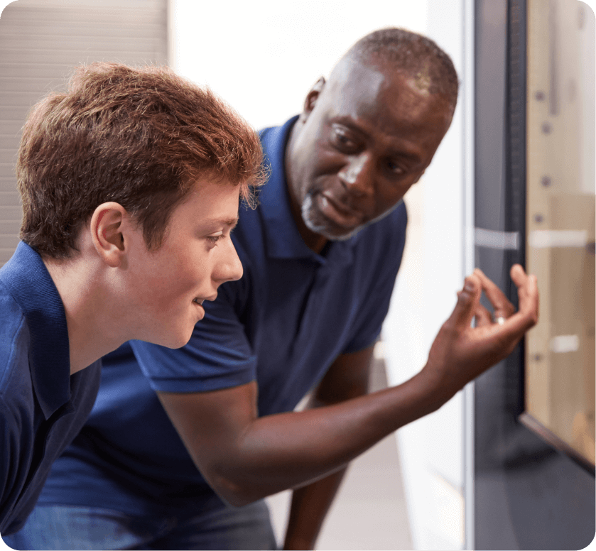 A man in a navy uniform is explaining to a younger man how to do a job task.